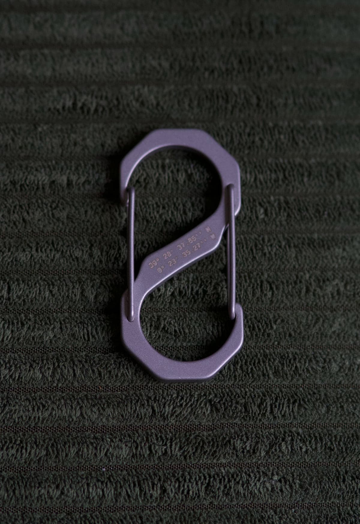 S-CARABINER back, engraved coordinates, on dark green fabric