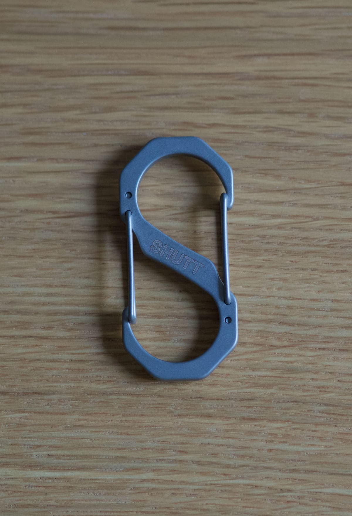 S-CARABINER front, SHUTT wordmark laser-engraved, on oak